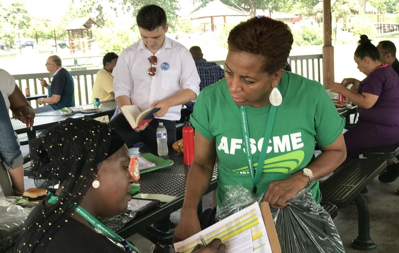 Fatmata Turay signs a PEOPLE card as member organizer Starr Suggs waits to award Turay with a new PEOPLE jacket.