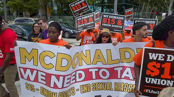 Supporters of the "Fight for $15" movement march with banners and posters.